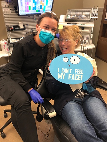 dentist and patient holding up a sign