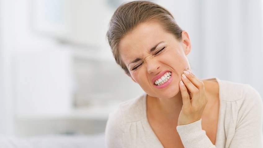 woman gritting teeth in pain