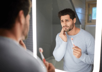 man holding cheek in pain