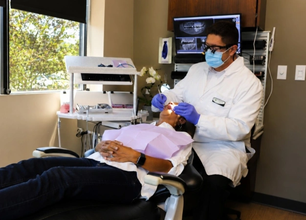 Male dentist in scrubs and mask examining a patient's teeth