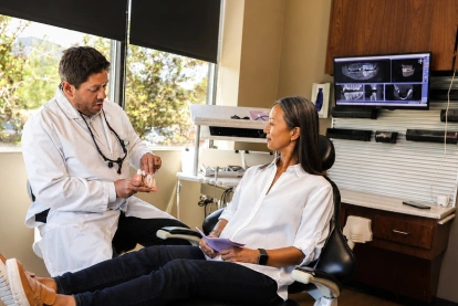 Dentist consulting with a patient in the treatment chair with digital X-rays displayed