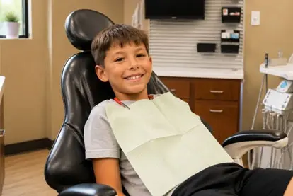 Smiling boy giving a thumbs up in a dental chair before treatment